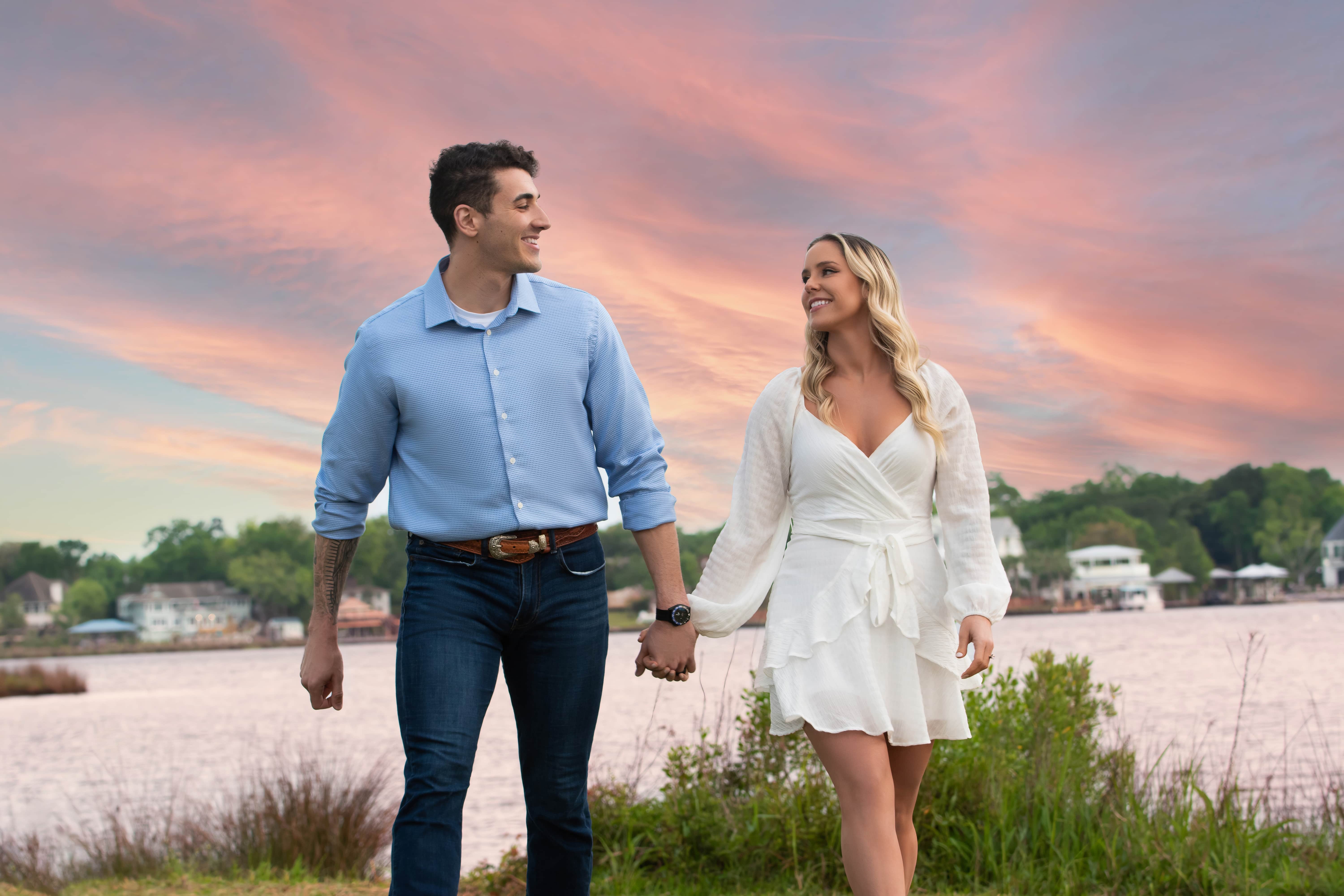Couple walking hand in hand along the water at sunset on the Mississippi Gulf Coast