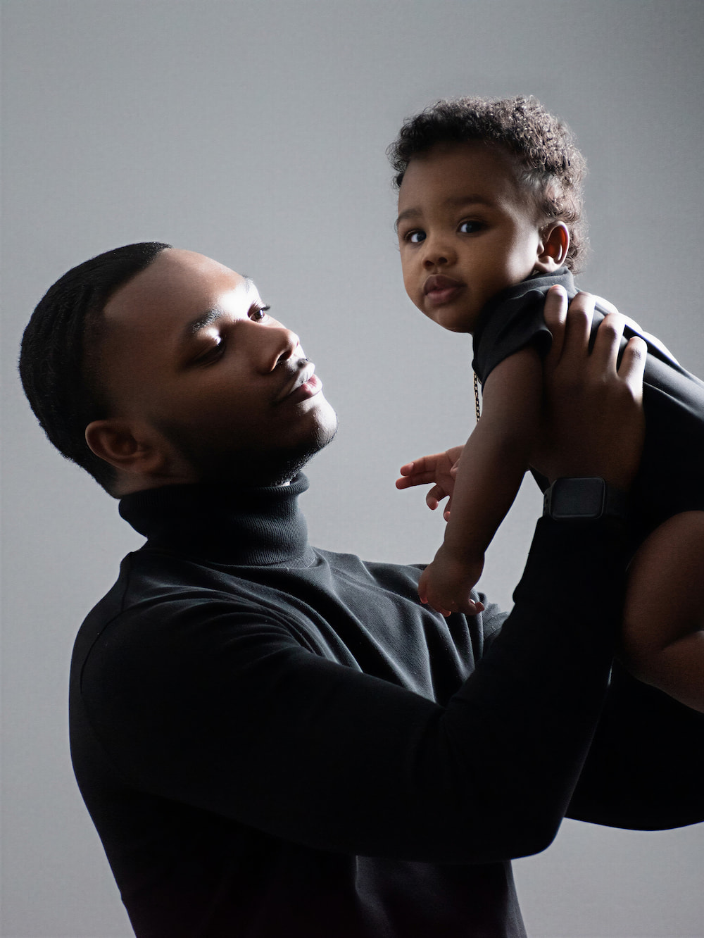 Father lifting his baby in the air during a studio portrait session in Biloxi, MS.