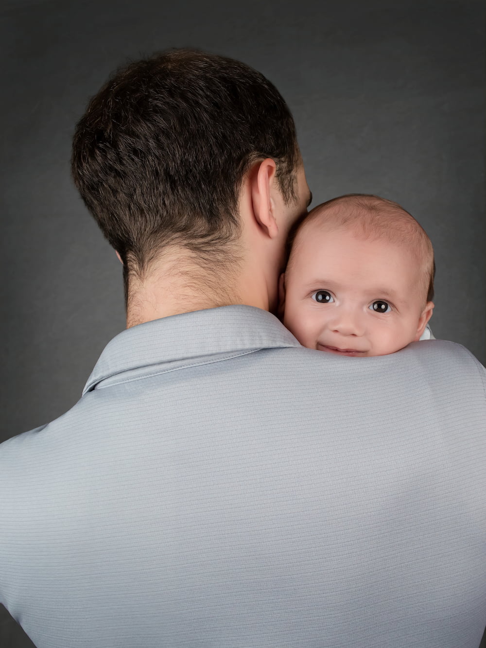 Smiling baby peeking over his father's shoulder at the DP Photography studio in Biloxi, MS.
